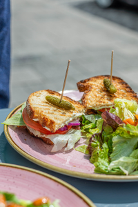 Ein Teller mit zwei Sandwichhälften und Salat aus dem veganen Café Om Nom Nom in Sendling